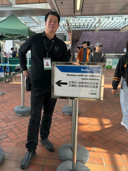 Security guard Tse Yiu Sum directs visitors at HKU's Exit A on March 6, 2026, during tourism flow management. Photo by Huang Shixian.
